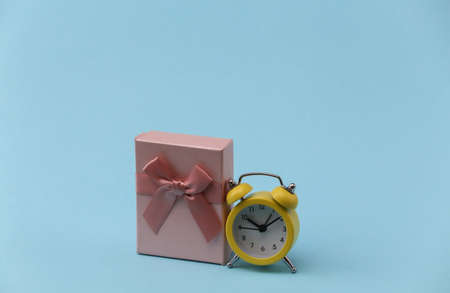 Yellow retro alarm clock and gift boxes on blue background.の写真素材