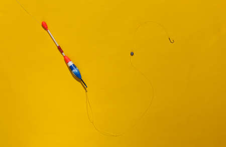 Fishing float with a hook on a bright yellow backgroundの写真素材
