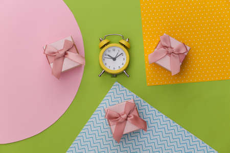 Gift boxes and alarm clock on creative colorful paper background. top view. minimalismの写真素材
