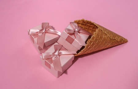 Ice cream waffle cone with gift boxes on pink bright pastel backgroundの写真素材