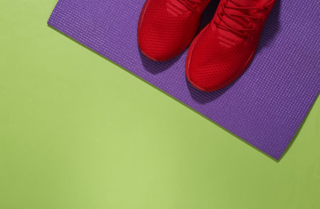 Red sport shoes and fitness mat on green background. Workout concept. top view. copy spaceの写真素材
