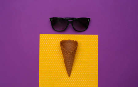 Ice cream waffle cones and sunglasses on purple yellow background. top viewの写真素材
