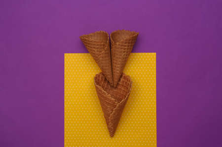 Ice cream waffle cones on purple yellow background. top viewの写真素材