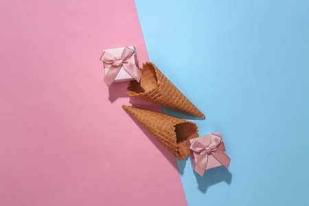 Ice cream waffle cones with gift boxes on pink and blue bright pastel background with deep shadow, top view. flat lay minimal compositionの写真素材