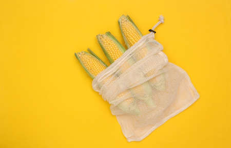Eco cotton bag with corn swings on yellow background. top view. flat layの写真素材