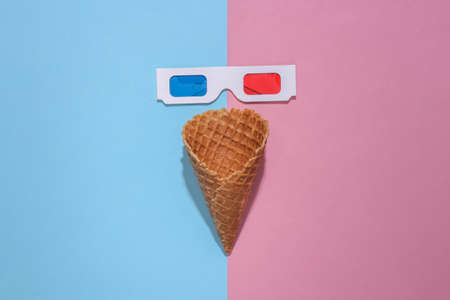 Ice cream waffle cone with 3d glasses on pink and blue bright pastel background with deep shadow, top view. flat lay minimal compositionの写真素材