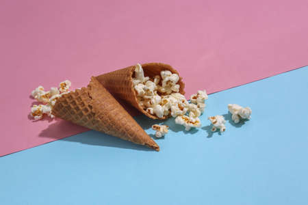 Ice cream waffle cones with popcorn on pink and blue bright pastel backgroundの写真素材