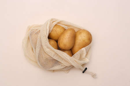 Potatoes in eco cotton bag on beige background. top view. flat layの写真素材