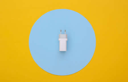 Charger adapter on yellow background with blue circle. top view. Minimalist flat layの写真素材