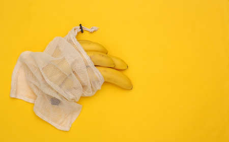 Eco cotton bag with ripe bananas on yellow background with copy space. top view. flat layの写真素材
