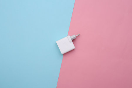 Charger adapter on a blue-pink pastel background. top view. Minimalist flat lay