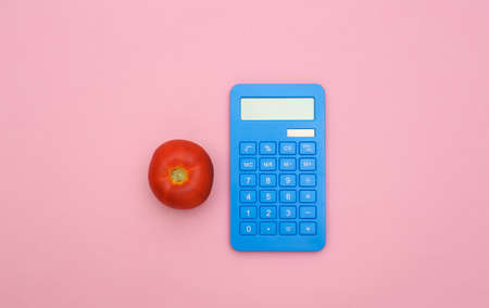 Tomato and calculator on pink pastel background. Flat lay composition. top viewの写真素材