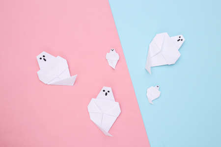 Origami ghosts on pink blue background. handmade halloween decor. top viewの写真素材