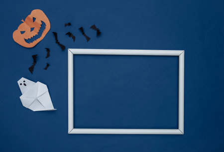 Paper cut Flying bats and halloween pumpkin, ghost on classic blue background with white frame for your text. Halloween background. copyspace. top viewの写真素材