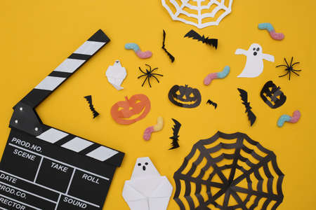 Movie Clapperboard and Handmade Halloween paper decor on yellow background. top view