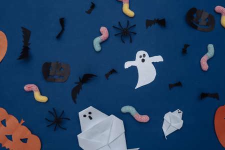 Handmade Halloween paper decor and gummy worms on classic blue background. Halloween background. top view. flat layの写真素材