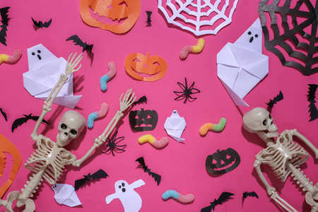 Handmade Halloween decor and skeleton, gummy worms on pink background. Halloween background. top view. flat layの写真素材