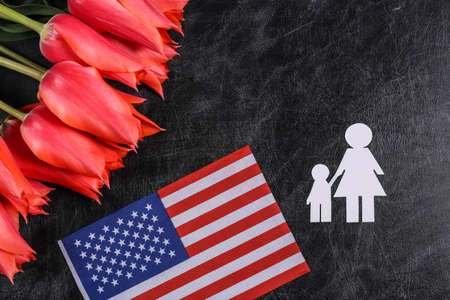 national holiday. knowledge day. Red tulips with paper figures mother and son, USA flag on chalk board. top view. back to schoolの写真素材