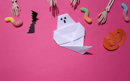 Handmade Halloween decor and skeleton hand, gummy worms on pink background. Halloween background. top view. flat layの写真素材