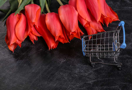 Bouquet of red tulips and shopping trolley on a chalk board backgroundの写真素材