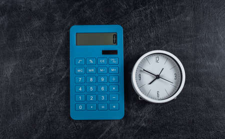 Calculator with clock on chalk board background. back to school. top view.の写真素材