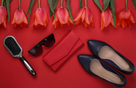 Red tulips and women's accessories on red background. Holiday Mother's Day or March 8th, birthday....