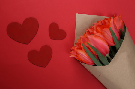 Bouquet of tulips and hearts on red background. Holiday Mother's Day, March 8th, birthday or Valentine's Day, marriage proposal. top viewの写真素材