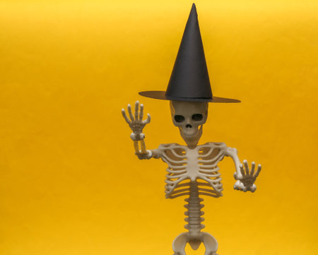 Skeleton in a witch's hat on a yellow background. Scary and Halloween themeの写真素材