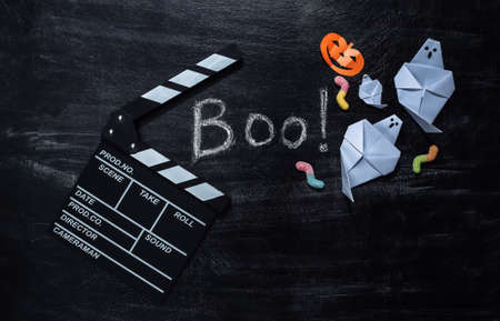 Movie Clapperboard and Chalk Lettering Boo! on a chalk board with helloween decor. Halloween themeの写真素材