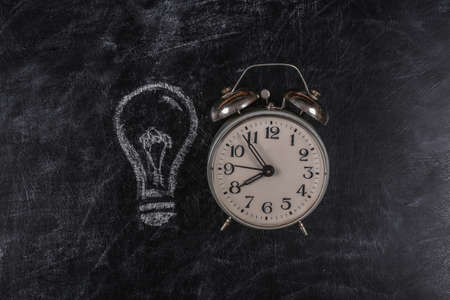 I have an idea! Alarm Clock with a painted light bulb on a chalk boardの写真素材