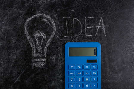 Calculator with a painted light bulb on chalk board. I have an idea!の写真素材