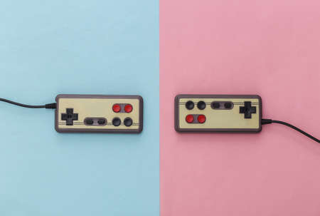 Two retro gamepads on a blue-pink background. Pastel color trend. Gaming, video games. Top view, minimalismの写真素材