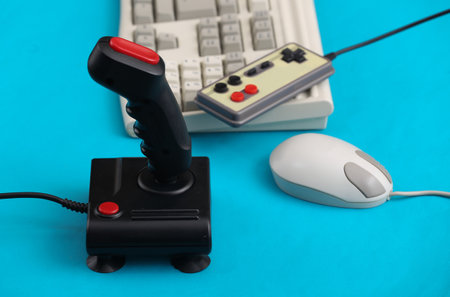 Old keyboard, joystick, gamepad and mouse on blue background. retro gaming. 80s.の写真素材