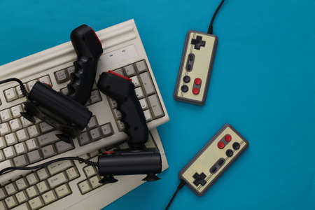 Old keyboard, joysticks and gamepads on blue background. retro gaming. 80s. top view. flat lay