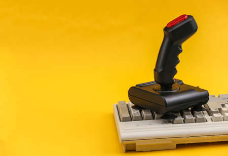 Retro joystick on old pc keyboard. yellow background. Attributes 80s, gamingの写真素材