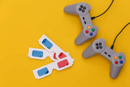 Retro gamepads, 3d glasses on yellow background. retro gaming. Stereo Video game, 80s. top view. flat layの写真素材