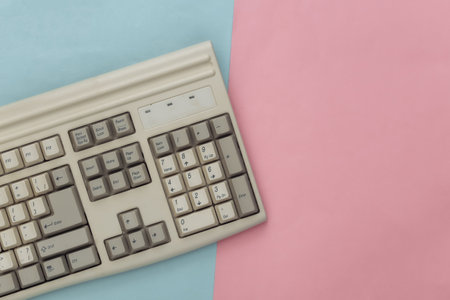Old pc keyboard on blue pink pastel background. top view. flat layの写真素材