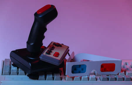 Retro joystick, gamepad with old pc keyboard and 3d glasses in pink blue gradient neon, holographic light. Attributes 80s, gaming, retro waveの写真素材