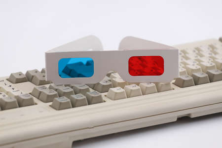 Anaglyph 3D glasses on old pc keyboard. white background. Retro Attributes 80s