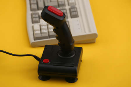 Old pc keyboard and joystick on yellow background. retro gaming. 80s.の写真素材