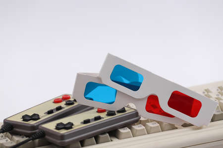 Retro gamepads, anaglyph 3D glasses on old pc keyboard. white background. Attributes 80sの写真素材