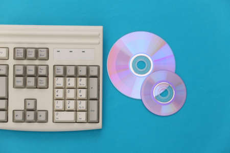 Retro electronics, pc technology 90s. PC keyboard, CD's on blue background. top view
