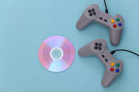 Two retro gamepads and CDs on blue background. Gaming, video game competition. Top view, minimalismの写真素材