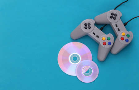 Retro gamepad and CD's on blue background. Gaming, video game competition. top viewの写真素材