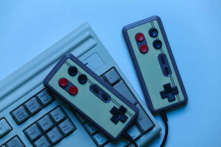 Old pc keyboard with gamepads in blue holographic light. retro wavesの写真素材