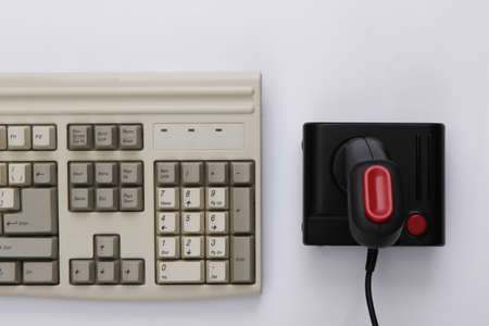 Old keyboard and joystick on white background. retro gaming. video game. 80s. top view. flat lay