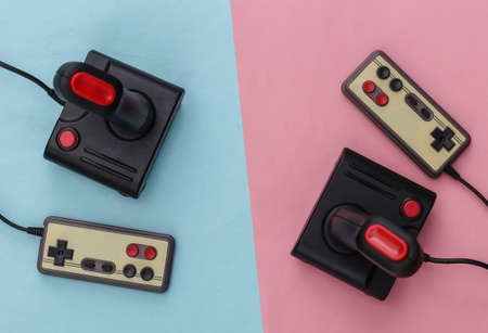 Retro joysticks and gamepads on blue-pink background. Pastel color trend. Gaming, video game competition. Top view, minimalismの写真素材