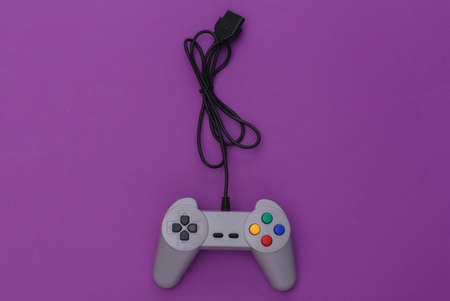 Wired retro gamepad (joystick) with wound cable on purple background. video game, gaming. top viewの写真素材
