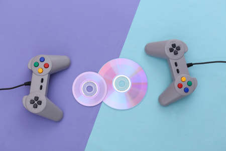 Retro gamepad and CD's on blue purple background. Gaming, video game competition. top viewの写真素材