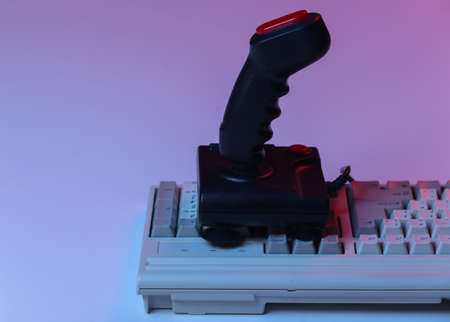 Retro joystick on old pc keyboard. Red blue gradient neon light. Attributes 80s, gaming. retro wavesの写真素材